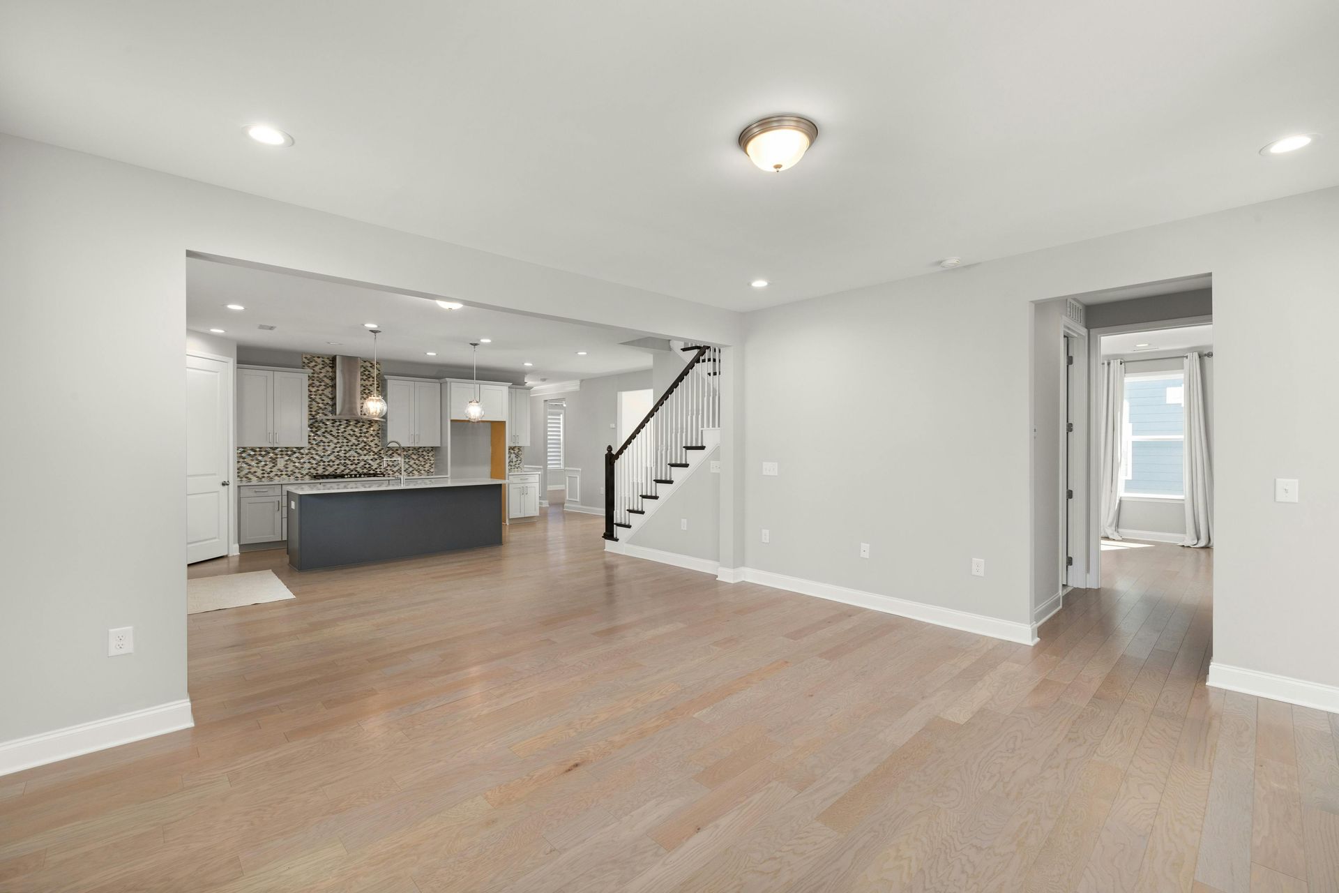Spacious open-concept living room with hardwood floors and modern kitchen design.
