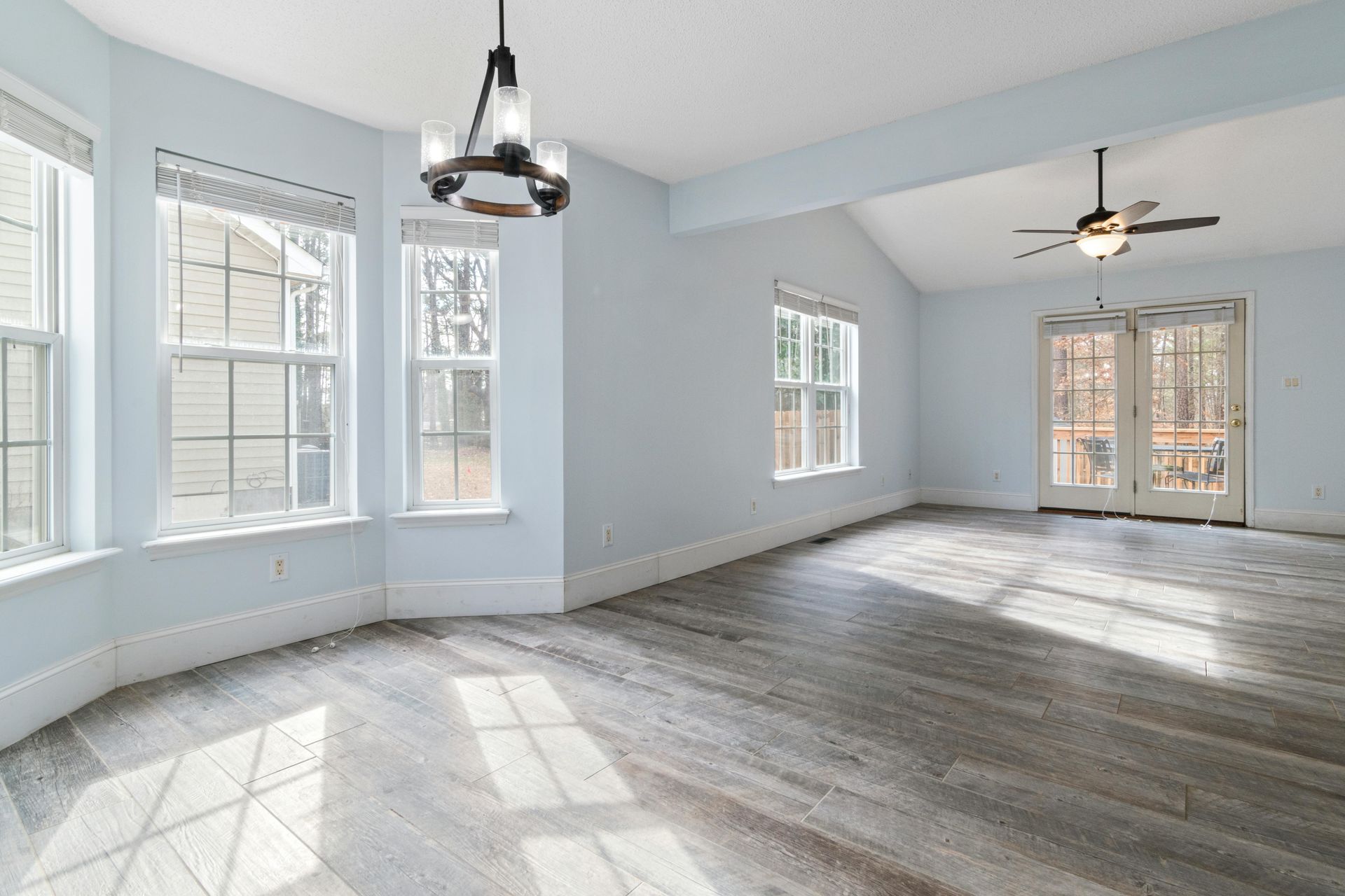 Bright empty living room with wooden floor and ceiling fan, ideal for interior design use.